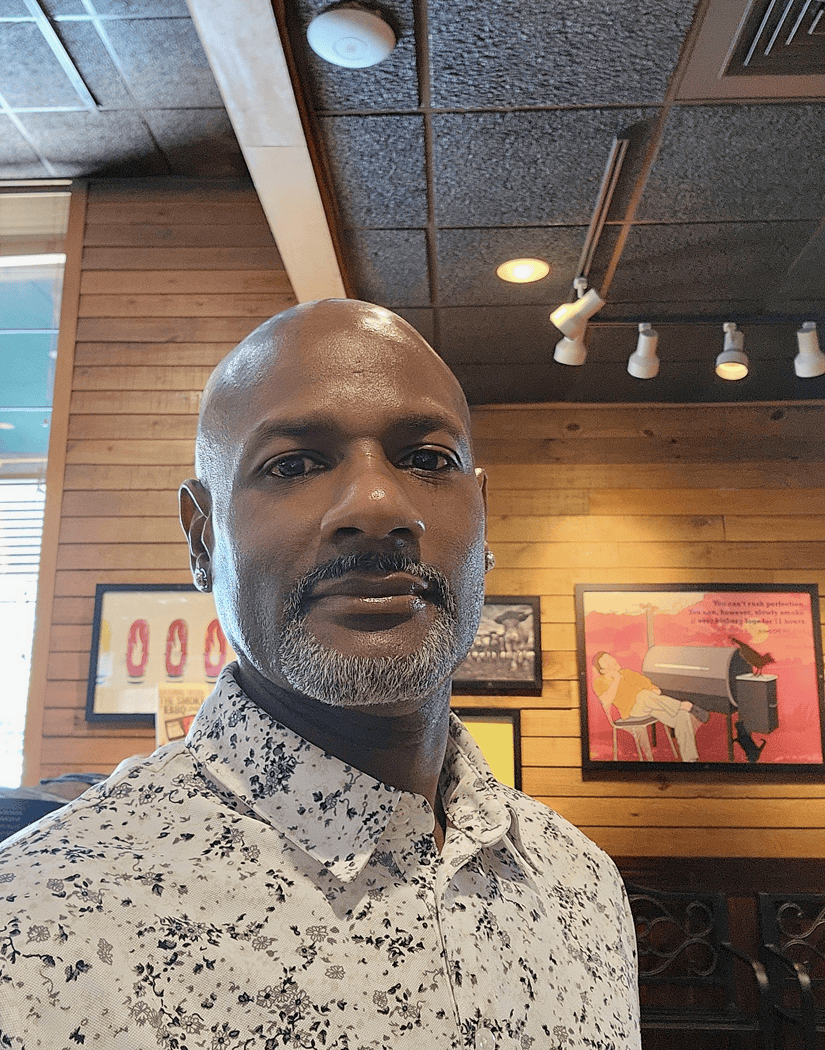Man in patterned shirt seated in café